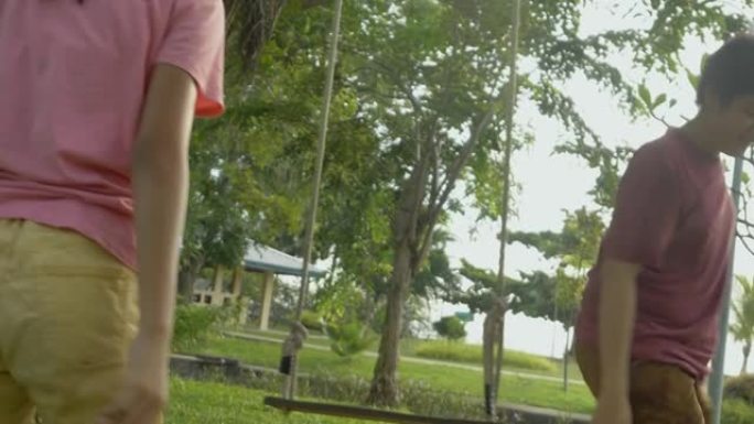 快乐的亚洲儿童在户外公园的树下玩秋千，生活方式的概念。