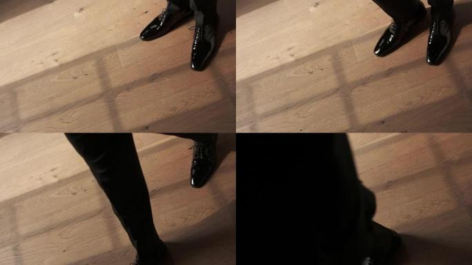 穿着西装和时髦鞋子的男人的腿。他迈出了一步。特殊活动的节日服装。黑色闪光鞋。