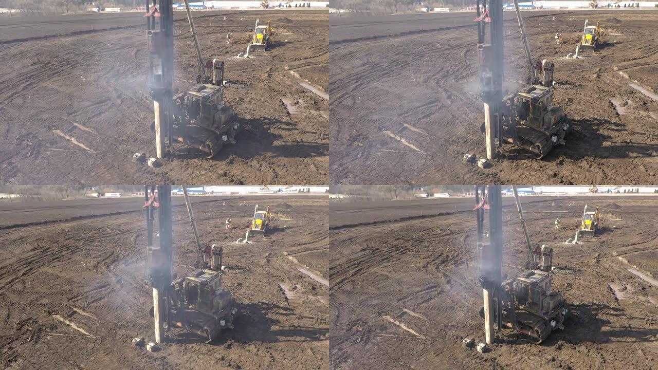 在施工现场开挖，带有隆隆声和烟雾的柴油打桩机将桩深入地面，以确保未来结构的基础强度
