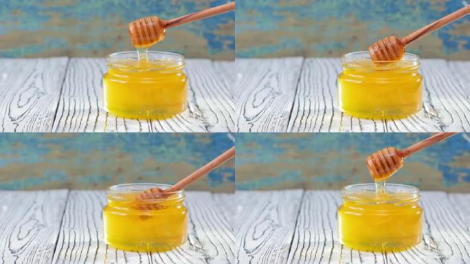 4k。玻璃罐子里的蜂蜜，在乡村木制背景上有蜂蜜铲斗
