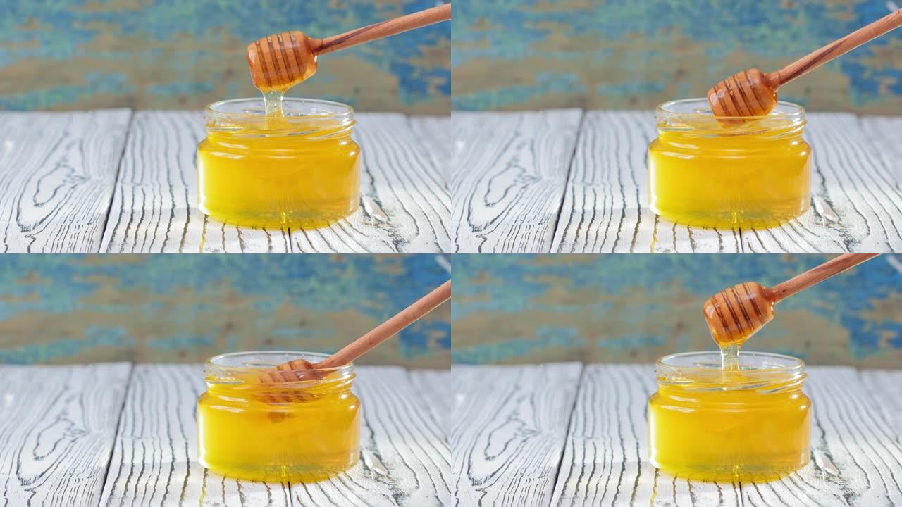 4k。玻璃罐子里的蜂蜜，在乡村木制背景上有蜂蜜铲斗