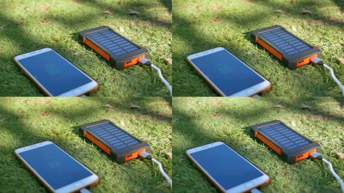 草坪上带有太阳能电池板的可充电移动电源组。连接到手机、平板电脑或智能手机并为其充电。带USB充电器的