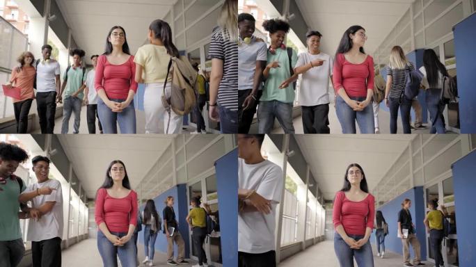 书呆子少女站在学校走廊上，男孩跟着大笑。美丽的被欺负的高加索高中生和公立学校的欺凌者的肖像。行为概念