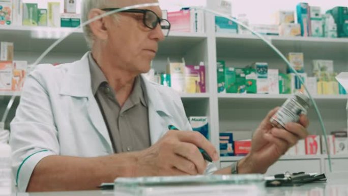 男药剂师拿着一罐药，阅读其成分并在文件夹中书写