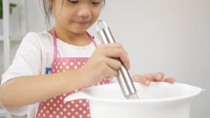 快乐的亚洲孩子在家里学习做饼干，女孩在搅拌碗里搅拌面粉。