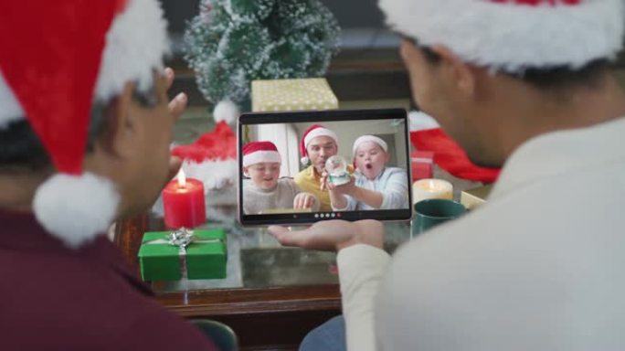 混血儿父子挥舞并使用平板电脑与家人在屏幕上进行圣诞节视频通话