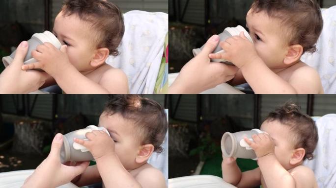 可爱的男孩在咖啡馆喝一杯水。孩子吃完后从外面的杯子里喝水
