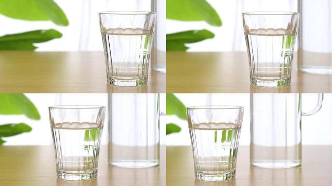 在桌子上的杯子里喝水。