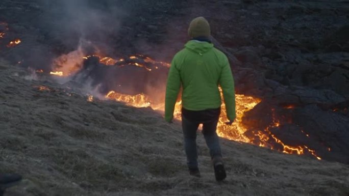 男子从爆发的fagradarsfjall火山走向熔岩流