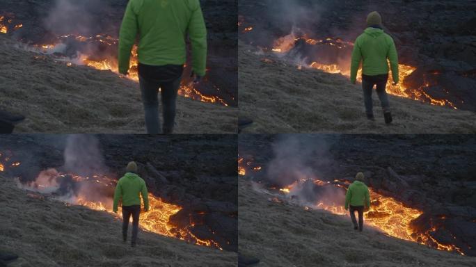 男子从爆发的fagradarsfjall火山走向熔岩流