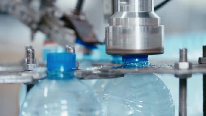 水厂工业机器在带水的塑料pet瓶上盖上盖子，特写