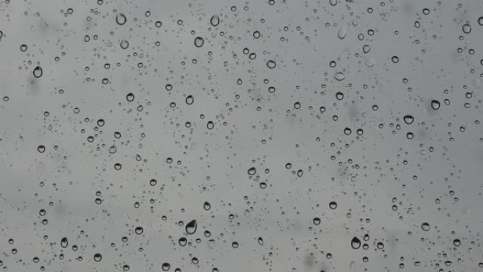 窗户玻璃上有大雨的水滴。水滴溅到玻璃上。暴雨降水主题的抽象模糊背景。选择性聚焦，