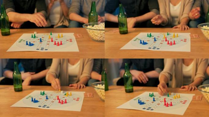 桌子的特写镜头，啤酒瓶，爆米花，游戏板在中间，棋子和纸牌排列，朋友，家人玩耍，扔骰子，一个人移动棋子