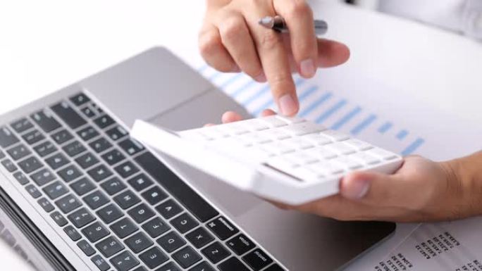 会计商人使用笔记本电脑和计算器，财务和税收系统的概念来分析房地产投资数据。