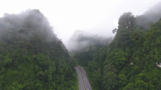 道路的宁静景象穿过带有雾的局部山脉。航拍视频