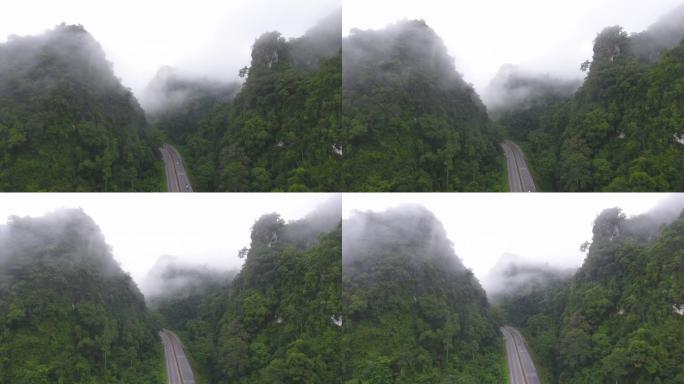 道路的宁静景象穿过带有雾的局部山脉。航拍视频