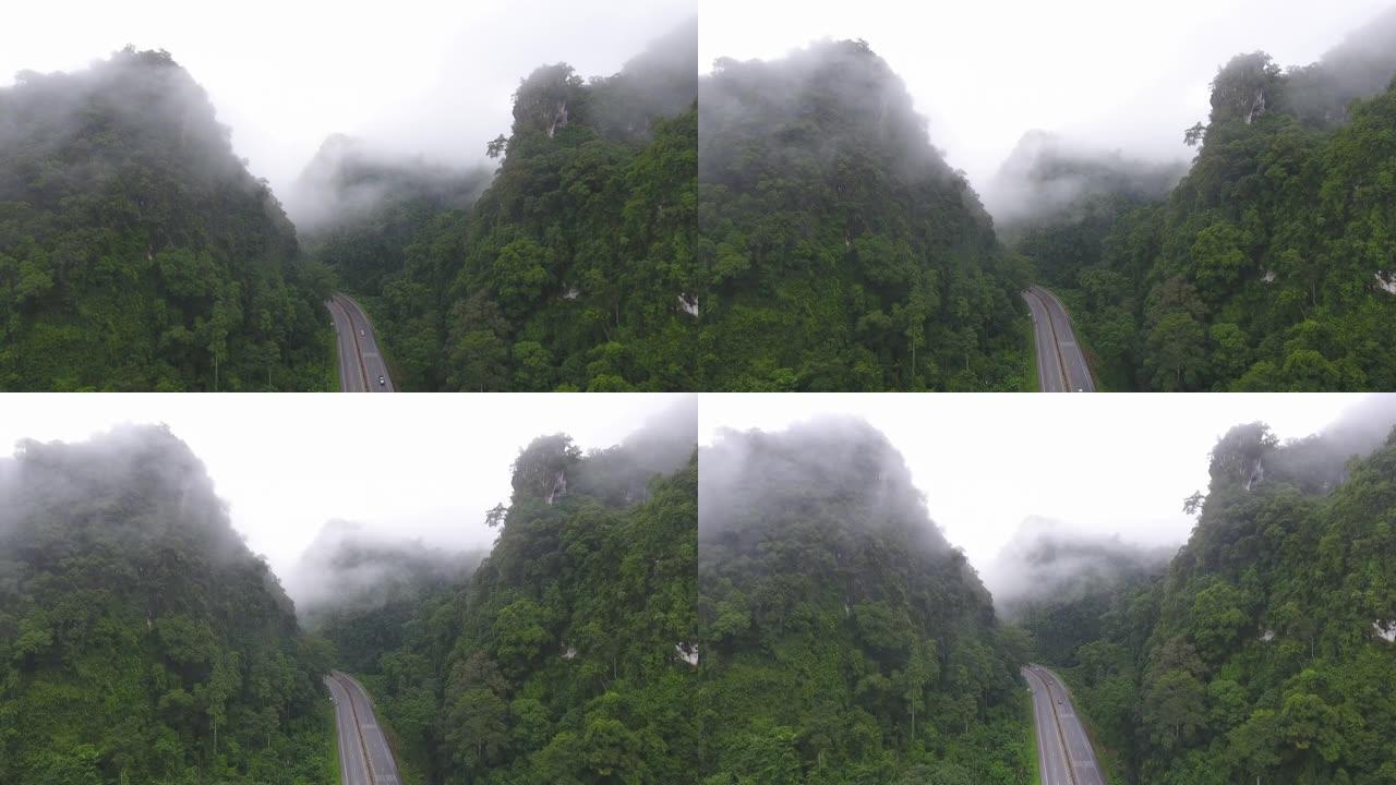 道路的宁静景象穿过带有雾的局部山脉。航拍视频