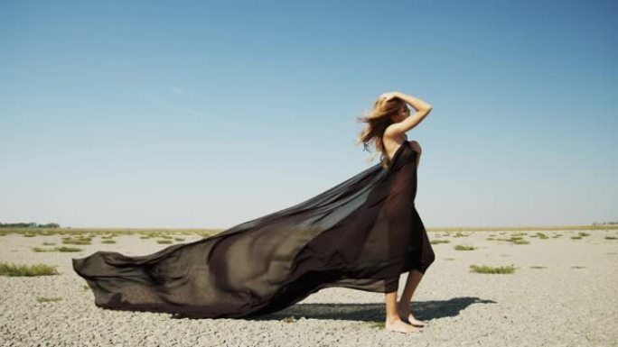 一幅穿着黑色布料的女人在沙漠中行走的画像