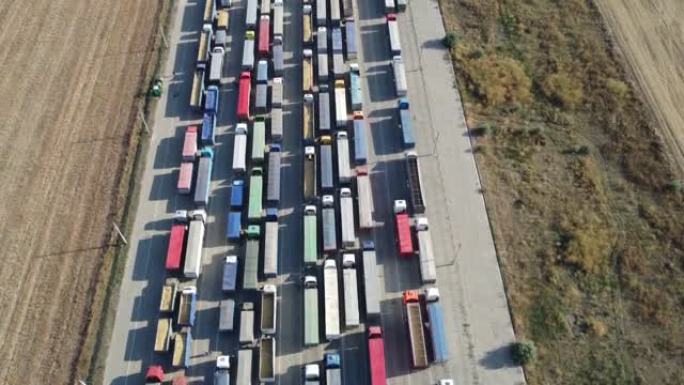 无人机飞过站在港口码头的一排排卡车，等待卸载。向其他国家出口谷物。物流公司。