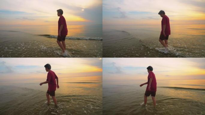 快乐的亚洲男孩在日出背景的海滩上散步和放松，生活方式的概念。