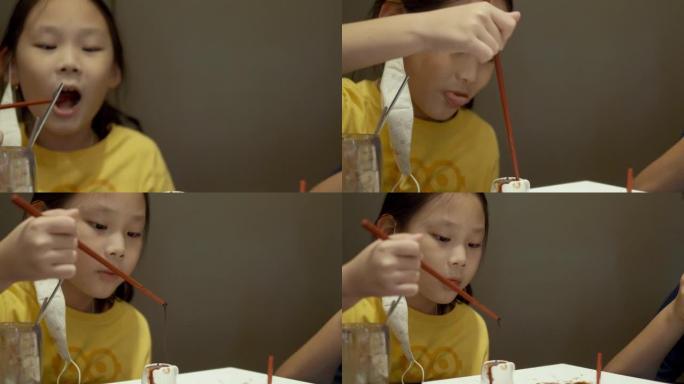 亚洲女孩在餐厅的餐桌上舔吸管和巧克力软糖，生活方式的概念。