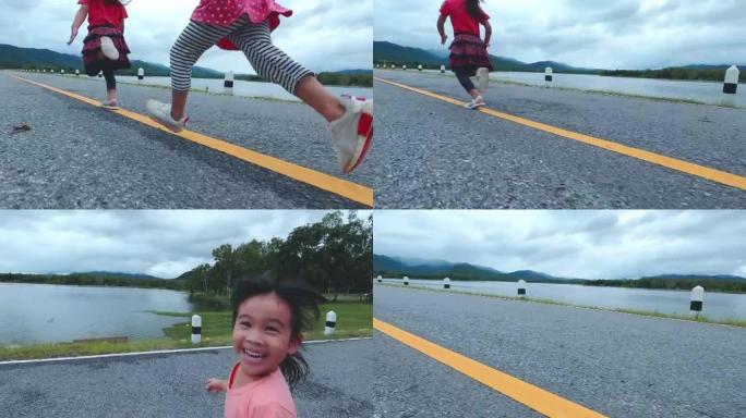 日落时，两个小姐妹沿着湖滨公路向前奔跑。童年幸福概念。