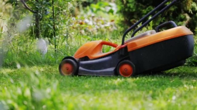 电动割草机割绿草。春夏季节在避暑别墅园艺。割草机在行动。