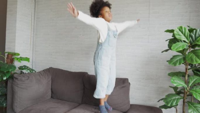 一个非洲裔美国孩子在客厅的沙发上跳跃。