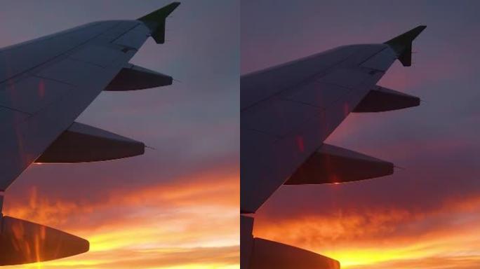 从机翼和夕阳的轮廓上的飞机窗户的视野。
