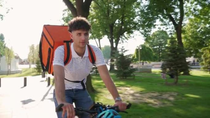 年轻的送货员骑着自行车在城市运送食物