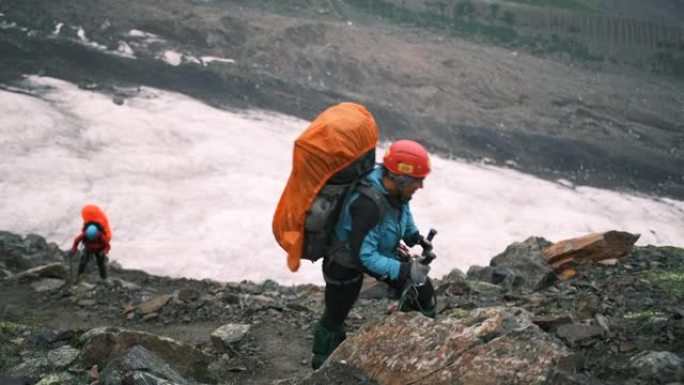 山里的一名妇女带着一个装有装备和登山杖的大背包爬上去。