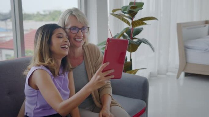 收养的亚洲青少年女儿和她的高加索继母在视频电话会议上向家人道别。互联网技术的现代家庭生活方式。