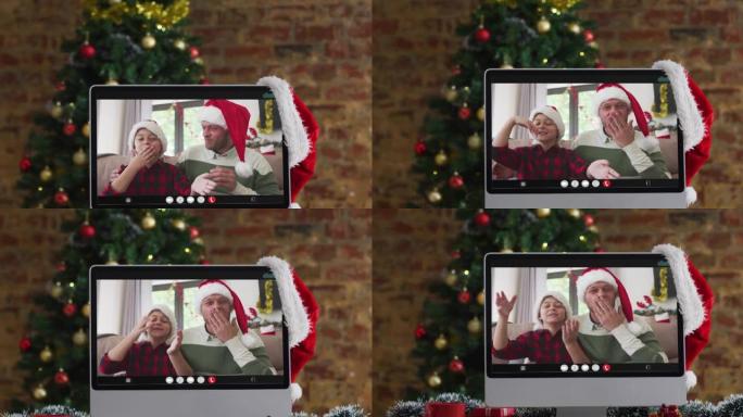 快乐的父亲和儿子在计算机上的视频通话中挥舞着圣诞装饰品和树
