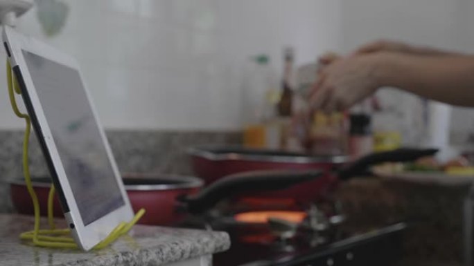 东南亚妇女使用数字平板电脑学习在线烹饪。