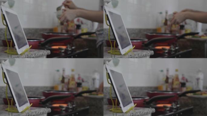 东南亚妇女使用数字平板电脑学习在线烹饪。