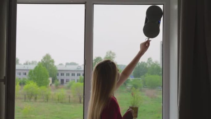 玻璃机器人清洁器上有杯形水龙头的女人洗窗户