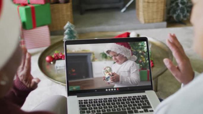 使用笔记本电脑与屏幕上的高加索男孩进行圣诞节视频通话的资深女性朋友