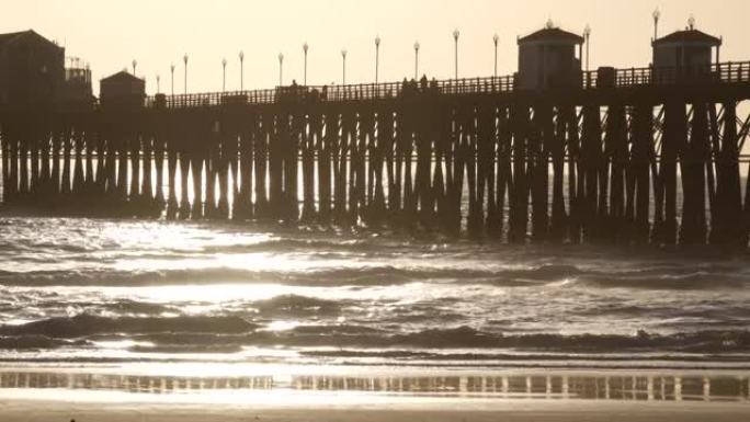 木桩码头，日落时的轮廓，美国加利福尼亚州，海滨。日落时阳光明媚的海浪。