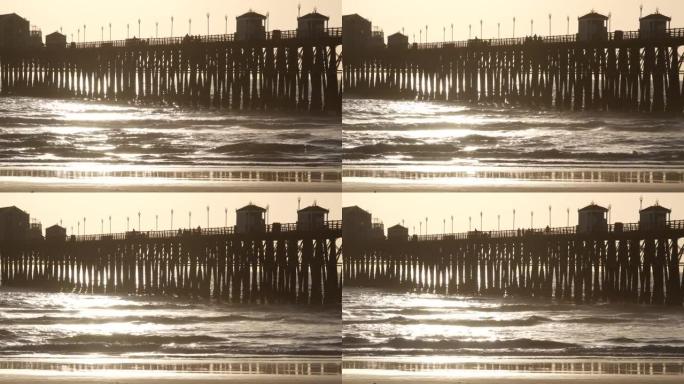 木桩码头，日落时的轮廓，美国加利福尼亚州，海滨。日落时阳光明媚的海浪。