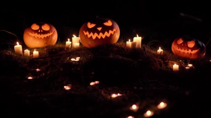 三个可怕的发光南瓜和闪电中燃烧的蜡烛的特写镜头。晚上后院的传统节日符号。令人毛骨悚然的神秘万圣节背景
