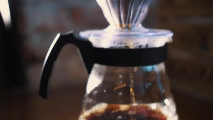 滴咖啡冲泡。特写。咖啡师将专用水壶中的沸水倒在传统滴灌玻璃水壶中的纸质过滤器中的现磨咖啡豆上