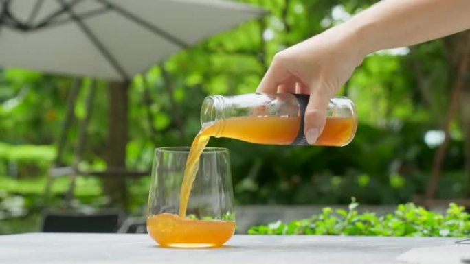 女人手倒康普茶饮料，发酵茶从玻璃瓶到玻璃