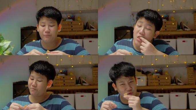 亚洲男孩晚上在家吃饼干，万圣节概念。