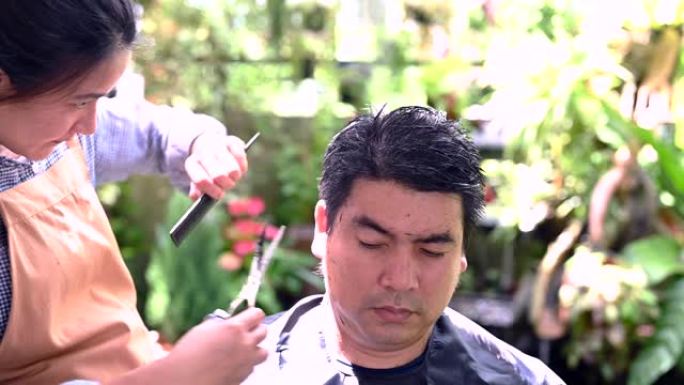 亚洲情侣理发是为了让他在家里焕然一新。花园里的沙龙和理发店。