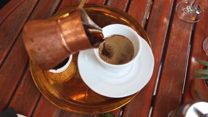 手将传统的热希腊咖啡放入玻璃杯中