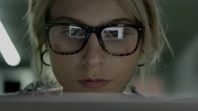 女人使用电脑和电脑屏幕光线从眼镜反射
