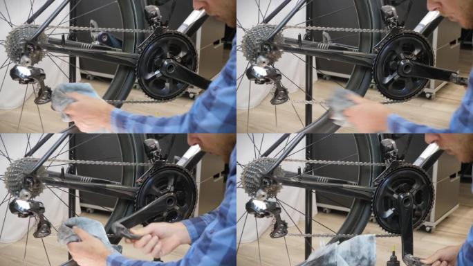 自行车维护。自行车机械师用超细纤维布清洁自行车链条。男性双手用布清洁自行车链条。自行车车间