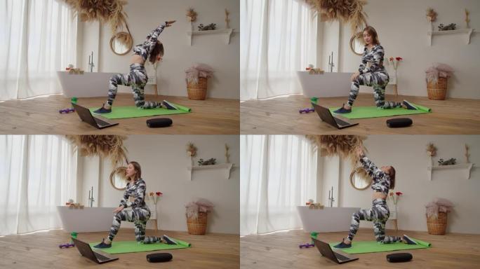 漂亮的运动健身女性，笔记本电脑放在运动垫上，在室内做新月姿势