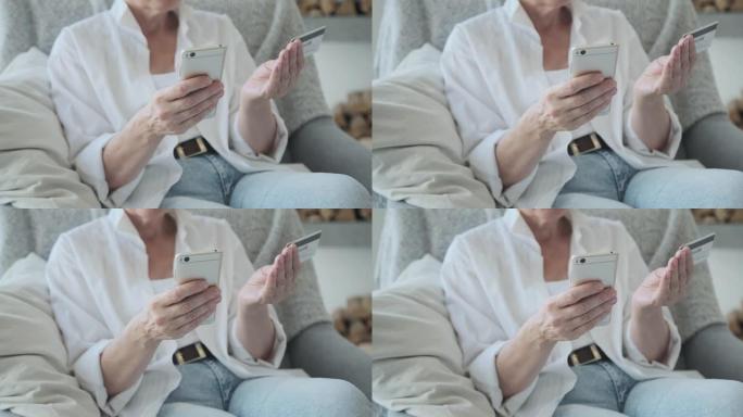 一个成熟的老年女性客户使用银行信用卡和手机的特写镜头。