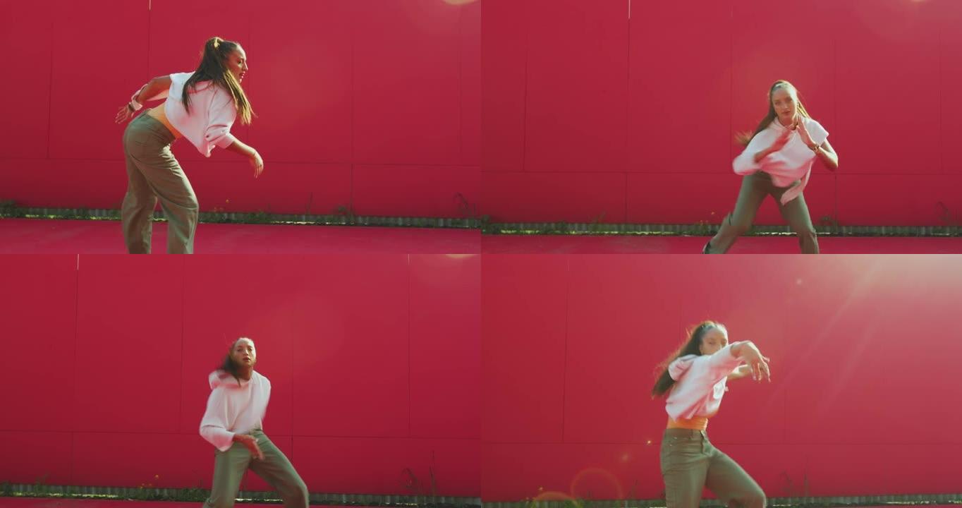 舞蹈学校广告视频。充满活力的年轻混血女孩在阳光下在红墙前跳舞
